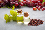 Fototapeta Dinusie - Grape seed oil in small bottle and bunch of grapes together.