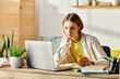 © LIGHTFIELD STUDIOS - A focused teenage girl studying at a wooden desk with a laptop open in front of her for e-learning.
