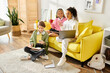 © LIGHTFIELD STUDIOS - Group of interracial teenage girls happily studying together on a sunny day, bonding over books on a bright yellow couch.