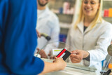 Fototapeta Panele - Customer using credit card to pay the bill for medications in a drugstore, pharmacy.