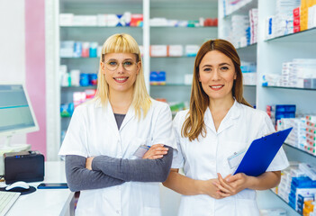 Portrait of two young pharmacists at the cash desk of pharmacy store.