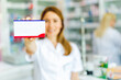 Female pharmacist holding up a box of medication in the pharmacy.