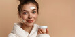 A woman is holding a white cream in her hand and smiling. Concept of happiness and contentment, as the woman is enjoying the moment. The cream could be a skincare product