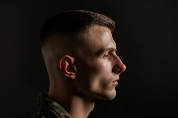 Wall Mural - Side profile of a young man showcasing a fresh buzz cut on a dark background