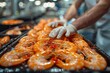Chef's gloved hands are meticulously organizing shrimp on a commercial food tray, emphasizing skilled food preparation