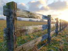 A Wooden Fence With A Few Spots Of Moss On It. The Fence Is In A Field With Grass And The Sun Is Shining On It