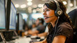 Computer supporter sitting in call center with headset on at computer and smiling, a webcare lady, brunette, with headse