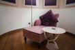 Luxury room corner with pink armchair, purple cushion, and white table in Zermatt, Switzerland. Intimate, elegant decor with diffused lighting for relaxation.