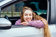 Hipster girl smiling with long dreadlocks braids hairstyle and shows tongue, car driver, travel concept.