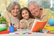 Grandparents with granddaughter drawing on the table