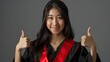 Elegant graduate. Asian charm, thumbs up. Inspire with sophistication
