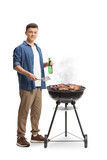 Fototapeta Panele - Young man making a barbecue and holding a bottle of beer