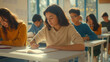 © Elena - Young female student sitting in classroom, writing notes. Hispanic girl attending lecture at college, school lesson. University students studying in class, passing test, exam
