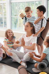 Poster - Group of children and female yoga instructor meditating in gym