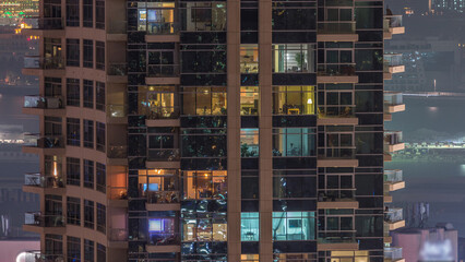 Poster - Rows of glowing windows with people in apartment building at night.