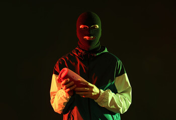 Poster - Handsome young man in balaclava with wireless portable speaker on black background