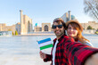 happy couple of tourists  taking a selfie with Registan as background in the city of Samarkand, Uzbekistan, Central Asia