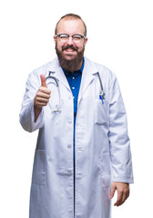 Sticker - Young caucasian doctor man wearing medical white coat over isolated background doing happy thumbs up gesture with hand. Approving expression looking at the camera with showing success.