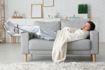 Canvas Print - Tired young man with plaid sleeping on sofa at home