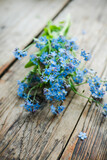 Fototapeta  - Small bouquet of blue forget-me-not flowers on the wooden background. Selective focus. Shallow depth of field.