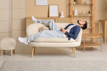 Canvas Print - Tired young man sleeping on couch at home