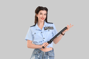 Canvas Print - Beautiful pin-up police officer with baton on grey background