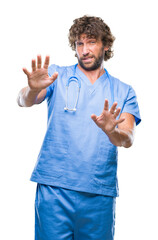 Wall Mural - Handsome hispanic surgeon doctor man over isolated background afraid and terrified with fear expression stop gesture with hands, shouting in shock. Panic concept.