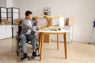 Wall Mural - Young man in wheelchair repairing chair at home