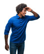 © Krakenimages.com - Afro american man over isolated background very happy and smiling looking far away with hand over head. Searching concept.