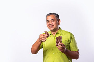 Wall Mural - Indian asian mid age man eating chocolate and smiling