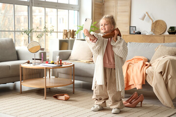 Poster - Cute little girl in adult clothes with heel taking selfie at home