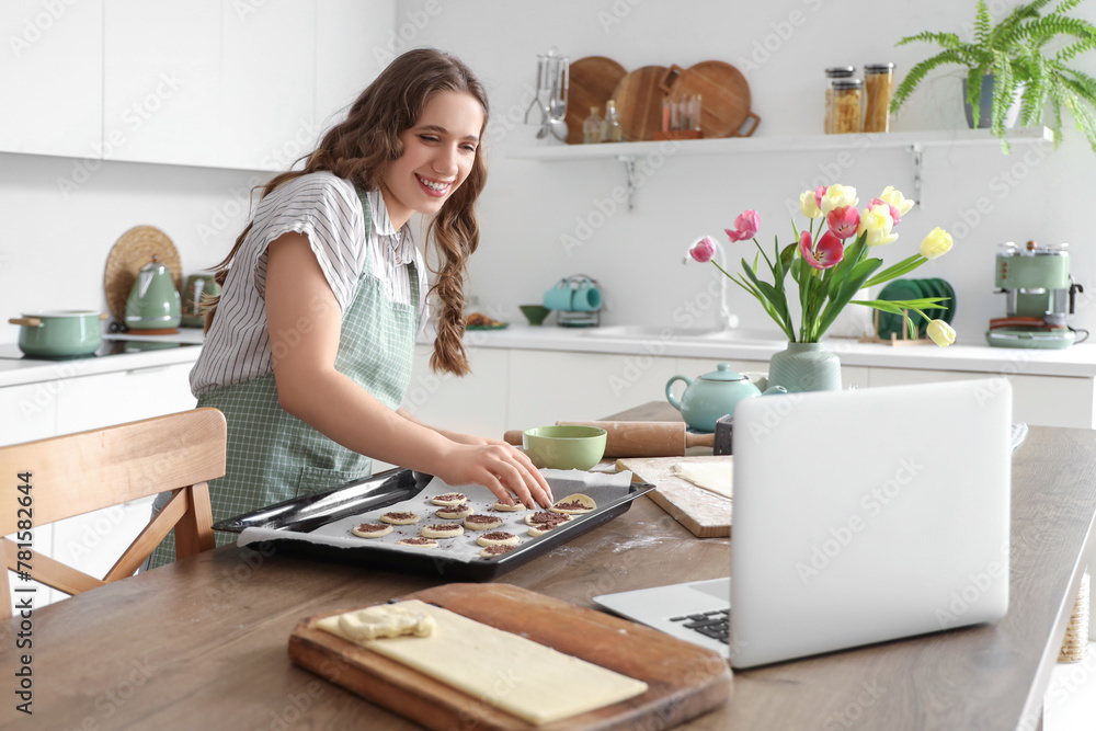 Young woman making chocolate cookies at table in kitchen