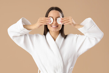 Poster - Young woman in bathrobe with cotton pads removing makeup on brown background