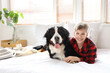 Little boy with Bernese mountain dog lying in bedroom