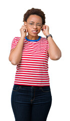 Canvas Print - Beautiful young african american woman wearing glasses over isolated background covering ears with fingers with annoyed expression for the noise of loud music. Deaf concept.