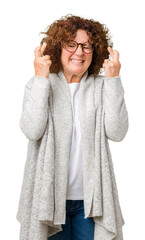 Poster - Beautiful middle ager senior woman wearing jacket and glasses over isolated background smiling crossing fingers with hope and eyes closed. Luck and superstitious concept.