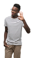 Wall Mural - Young african american man wearing glasses and navy t-shirt smiling positive doing ok sign with hand and fingers. Successful expression.