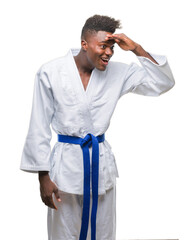 Wall Mural - Young african american man over isolated background wearing kimono very happy and smiling looking far away with hand over head. Searching concept.