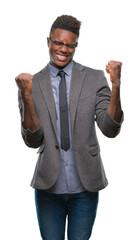 Wall Mural - Young african american business man over isolated background very happy and excited doing winner gesture with arms raised, smiling and screaming for success. Celebration concept.