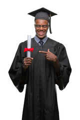 Wall Mural - Young graduated african american man holding degree over isolated background very happy pointing with hand and finger