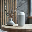 A smart speaker sits on a wooden table beside a ceramic vase with willow branches