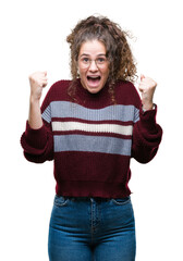 Wall Mural - Beautiful brunette curly hair young girl wearing glasses over isolated background celebrating surprised and amazed for success with arms raised and open eyes. Winner concept.