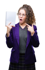 Sticker - Young brunette student girl wearing school uniform holding a notebook over isolated background very happy pointing with hand and finger