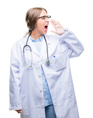 Canvas Print - Beautiful young blonde doctor woman wearing medical uniform over isolated background shouting and screaming loud to side with hand on mouth. Communication concept.