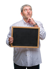 Poster - Handsome senior teacher man holding blackboard over isolated background serious face thinking about question, very confused idea