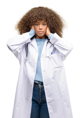 Poster - African american doctor woman, medical professional working covering ears ignoring annoying loud noise, plugs ears to avoid hearing sound. Noisy music is a problem.