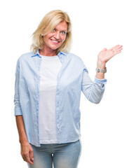 Sticker - Middle age blonde woman over isolated background smiling cheerful presenting and pointing with palm of hand looking at the camera.