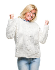 Sticker - Middle age blonde woman wearing winter sweater over isolated background very happy and excited doing winner gesture with arms raised, smiling and screaming for success. Celebration concept.