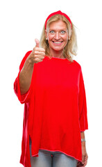 Wall Mural - Middle age blonde woman over isolated background doing happy thumbs up gesture with hand. Approving expression looking at the camera with showing success.