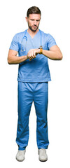 Poster - Handsome doctor man wearing medical uniform over isolated background Checking the time on wrist watch, relaxed and confident